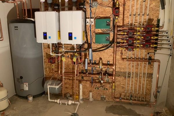 Two wall hung condensing boilers with a copper circulator manifold in a Denver basement