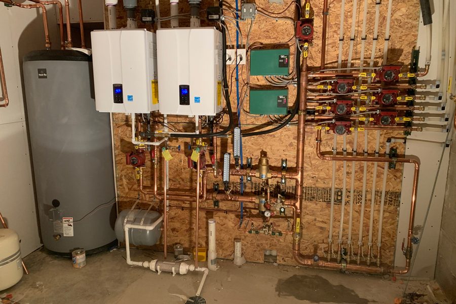 Two wall hung condensing boilers with a copper circulator manifold in a Denver basement